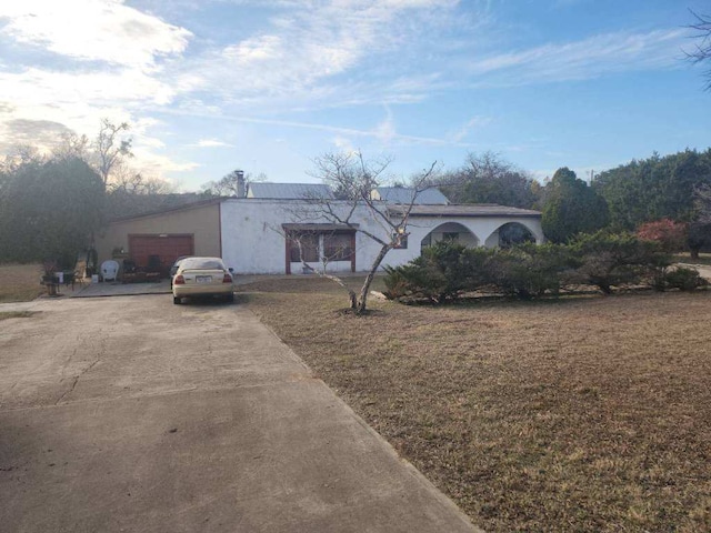 view of front facade with an attached garage, driveway, and stucco siding