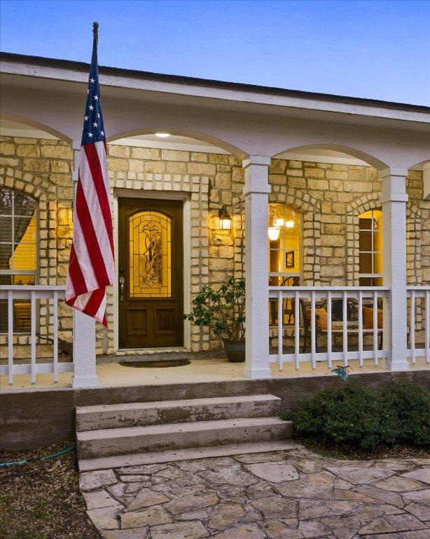 property entrance featuring a porch and stone siding