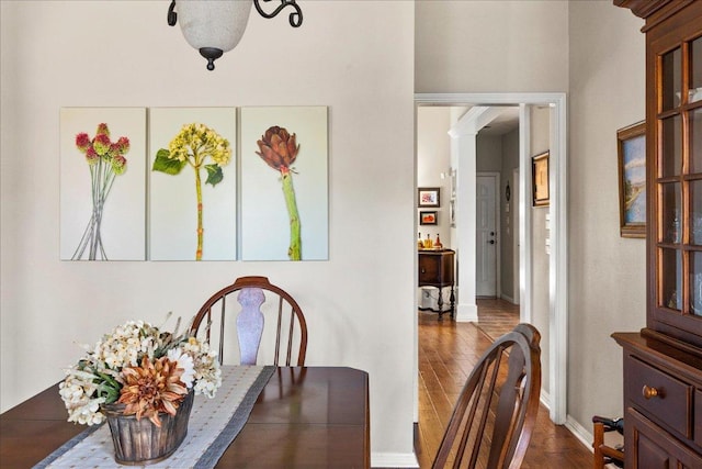 dining space with hardwood / wood-style flooring, baseboards, and ornate columns