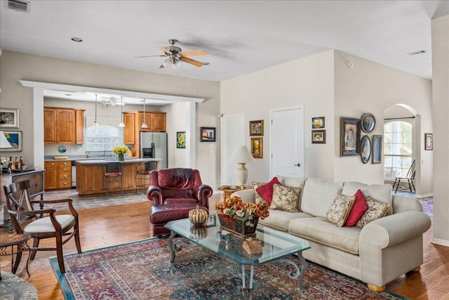 living room with a ceiling fan, visible vents, light wood-style floors, and a healthy amount of sunlight