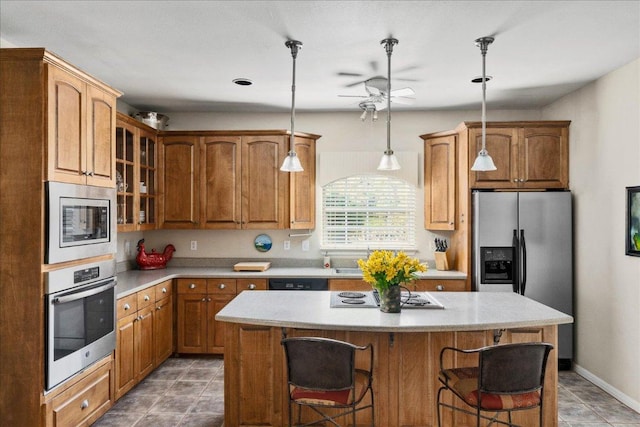 kitchen featuring a center island, glass insert cabinets, a ceiling fan, appliances with stainless steel finishes, and a breakfast bar area