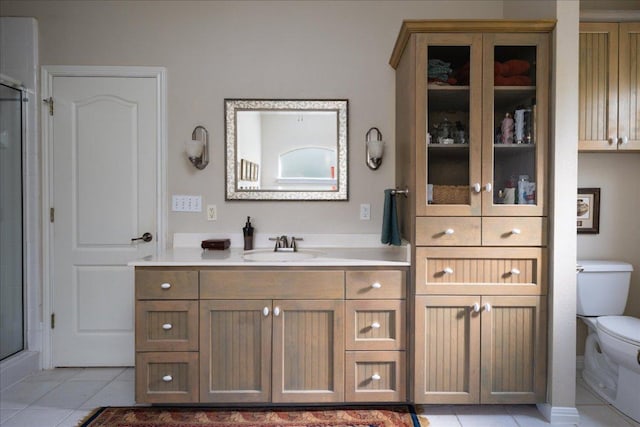 bathroom with a shower with shower door, tile patterned floors, vanity, and toilet