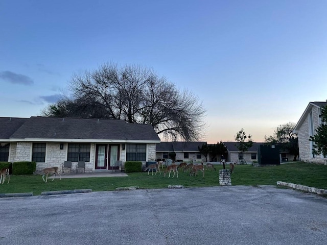 ranch-style home with a patio area, stone siding, and a front yard