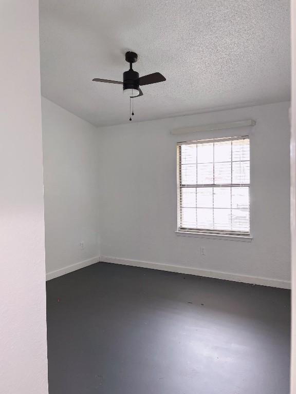 unfurnished room featuring finished concrete flooring, a textured ceiling, a ceiling fan, and baseboards