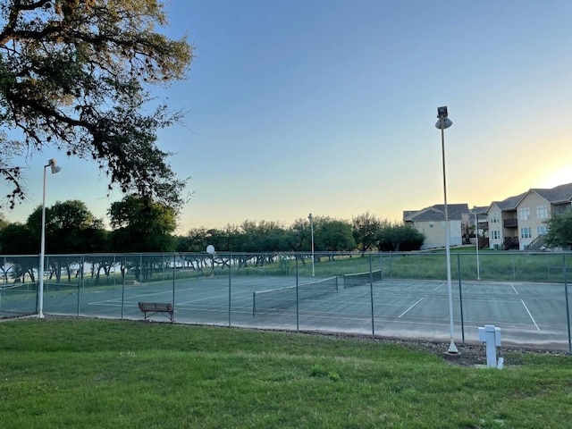 view of tennis court featuring a yard and fence
