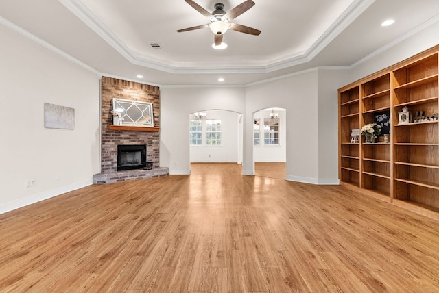 2800 Lomas Rodando Calzada Rd, Kempner, TX 76539 - unfurnished living room with a raised ceiling, arched walkways, ceiling fan, a fireplace, and crown molding