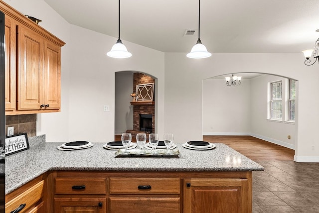2800 Lomas Rodando Calzada Rd, Kempner, TX 76539 - kitchen featuring a peninsula, arched walkways, a fireplace, light stone countertops, and decorative light fixtures