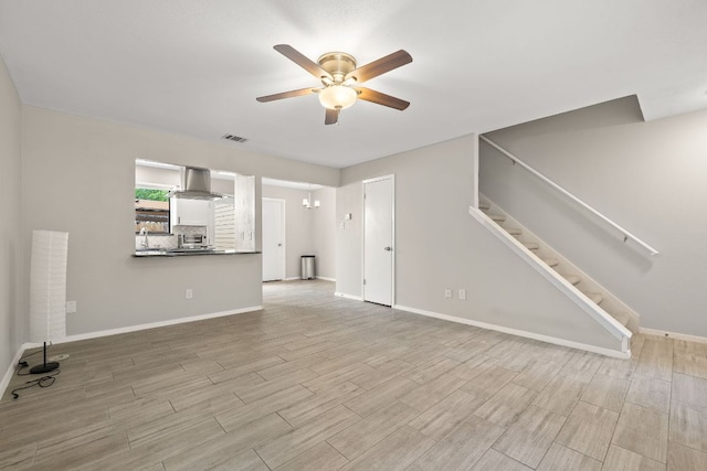 unfurnished living room featuring wood finished floors, visible vents, a ceiling fan, and stairway