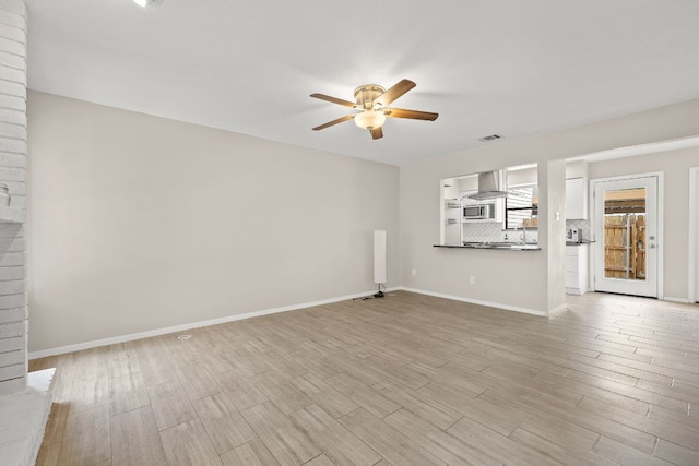 unfurnished living room featuring baseboards, a ceiling fan, light wood finished floors, and visible vents
