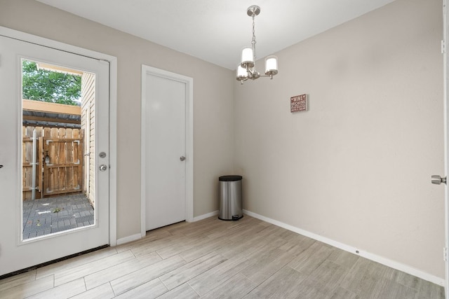 empty room with light wood finished floors, baseboards, and a notable chandelier