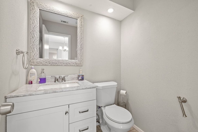 bathroom with visible vents, toilet, vanity, and an inviting chandelier