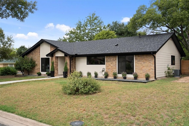 ranch-style home with brick siding, central air condition unit, roof with shingles, and a front yard