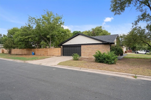 exterior space with brick siding, an attached garage, fence, and driveway