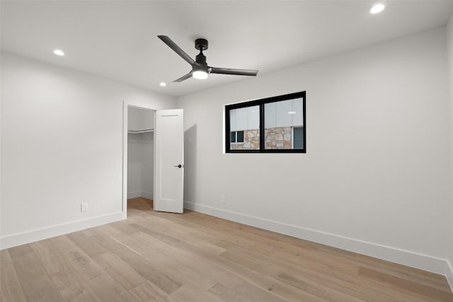 unfurnished bedroom featuring baseboards, recessed lighting, light wood-style floors, ceiling fan, and a walk in closet