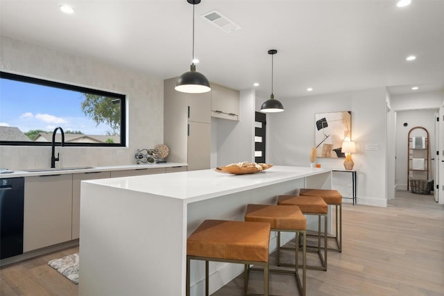 kitchen featuring light wood finished floors, light countertops, visible vents, modern cabinets, and a sink