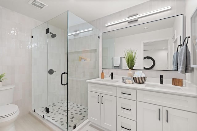 bathroom with a shower stall, visible vents, toilet, and a sink