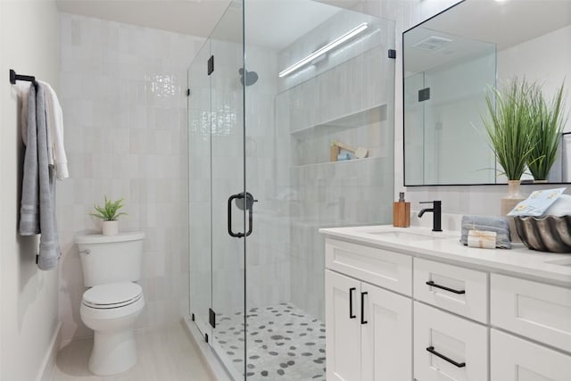bathroom with a shower stall, tile patterned floors, visible vents, toilet, and vanity