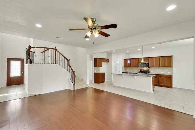 unfurnished living room featuring recessed lighting, light wood-style floors, stairs, and ceiling fan