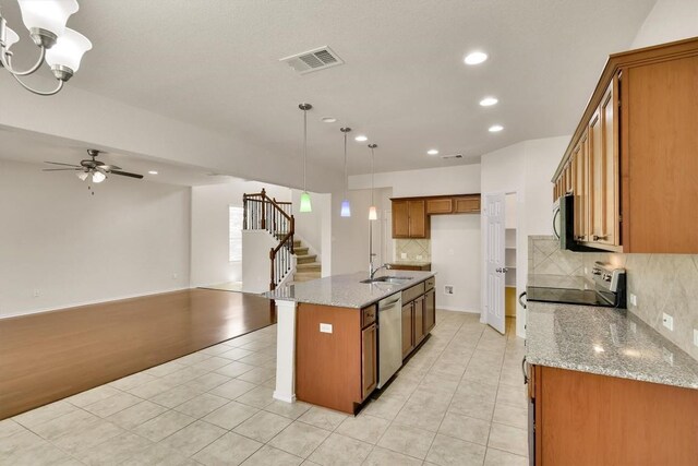 kitchen featuring tasteful backsplash, open floor plan, recessed lighting, brown cabinets, and appliances with stainless steel finishes
