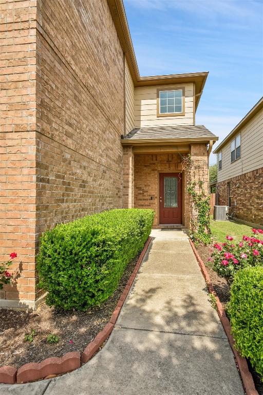view of exterior entry featuring brick siding and cooling unit