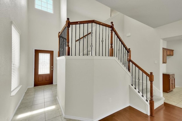 staircase with tile patterned flooring, a towering ceiling, and baseboards