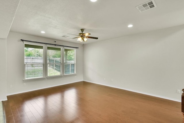 spare room with a ceiling fan, wood finished floors, and visible vents