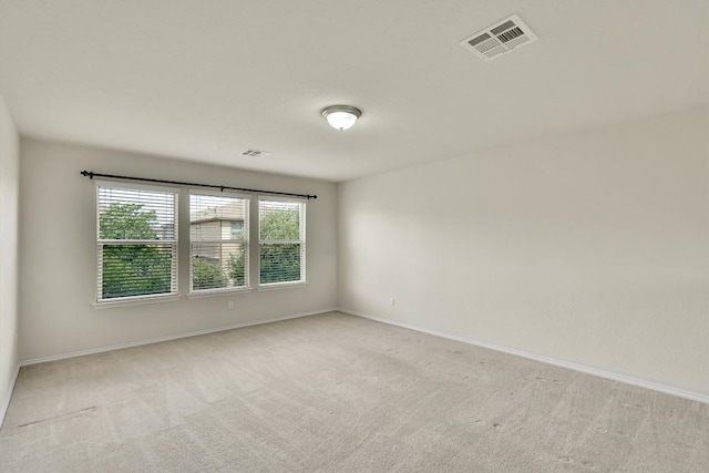 empty room featuring baseboards, visible vents, and light colored carpet