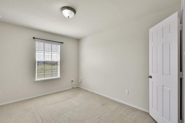 empty room featuring light carpet and baseboards