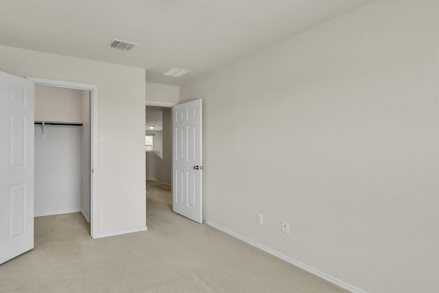 unfurnished bedroom with a spacious closet, visible vents, light carpet, a closet, and baseboards
