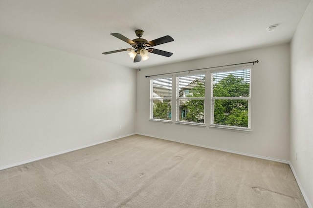 spare room featuring ceiling fan, baseboards, and light colored carpet