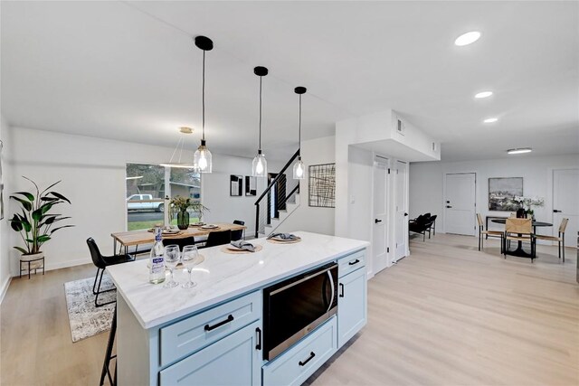 5000 Pack Saddle Pass, Austin, TX 78745 - kitchen featuring stainless steel microwave, light wood-style floors, a center island, pendant lighting, and light stone counters
