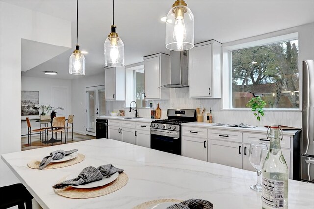 5000 Pack Saddle Pass, Austin, TX 78745 - kitchen with gas range, wall chimney range hood, light stone countertops, pendant lighting, and white cabinets