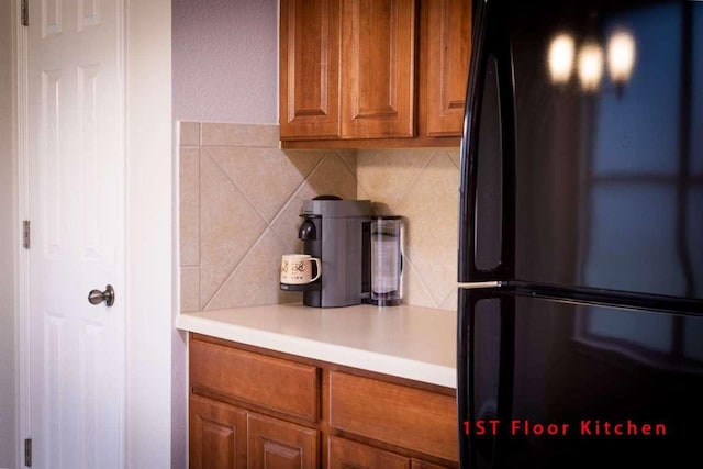 102 Buck Shot Ct, Bastrop, TX 78602 - kitchen with freestanding refrigerator, brown cabinetry, tasteful backsplash, and light countertops