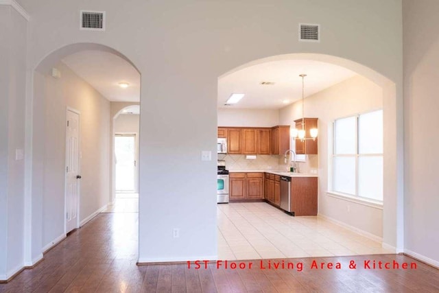 102 Buck Shot Ct, Bastrop, TX 78602 - kitchen with appliances with stainless steel finishes, brown cabinets, light countertops, tasteful backsplash, and a chandelier