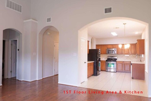 102 Buck Shot Ct, Bastrop, TX 78602 - kitchen featuring appliances with stainless steel finishes, light countertops, backsplash, brown cabinets, and light wood-style floors
