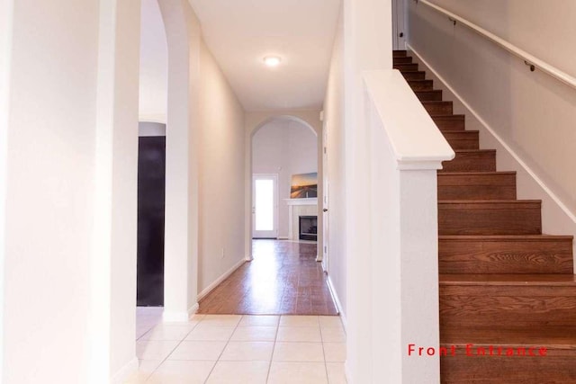 102 Buck Shot Ct, Bastrop, TX 78602 - stairway featuring tile patterned flooring, arched walkways, baseboards, and a tiled fireplace
