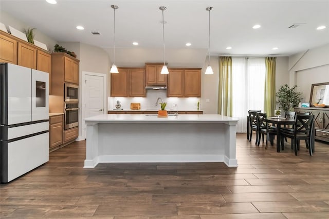 kitchen with light countertops, appliances with stainless steel finishes, dark wood-style floors, and brown cabinets
