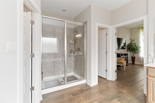 full bath featuring baseboards, a shower stall, wood finish floors, and vanity