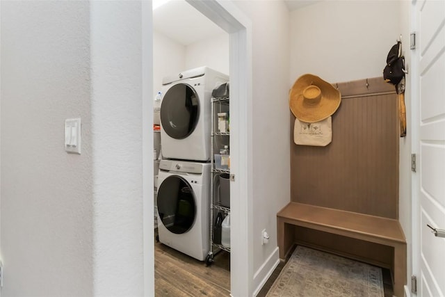 clothes washing area featuring wood finished floors, stacked washer and clothes dryer, and laundry area