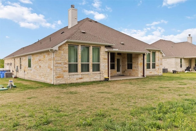 back of property with a chimney, central AC, a patio, stone siding, and roof with shingles