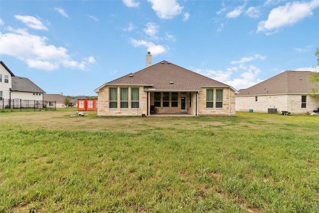 back of property with central air condition unit, a chimney, fence, a yard, and a patio