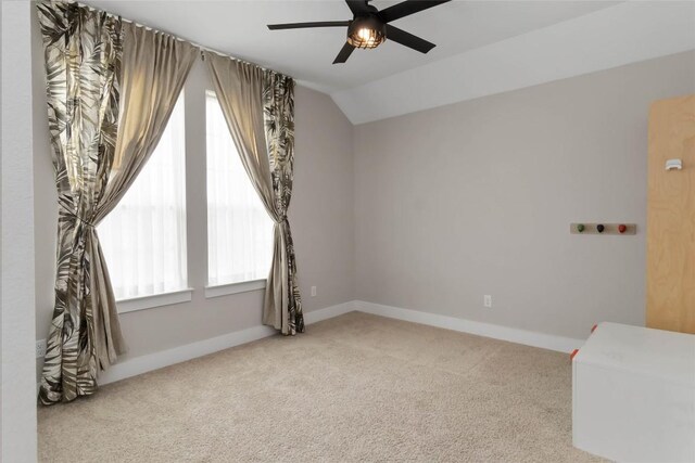carpeted spare room with ceiling fan, baseboards, and lofted ceiling