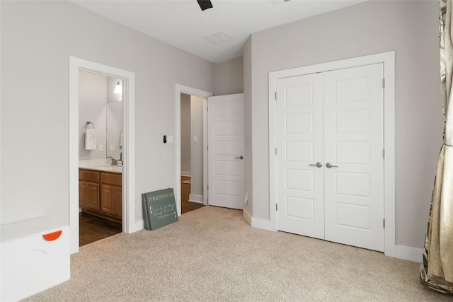 unfurnished bedroom with carpet, a sink, ensuite bath, a closet, and baseboards