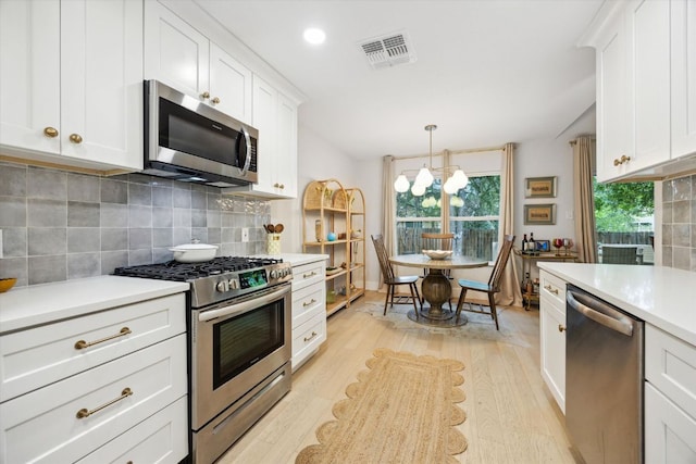 2602 Baxter Dr, Austin, TX 78745 - kitchen with stainless steel appliances, light wood-style flooring, light countertops, tasteful backsplash, and white cabinets