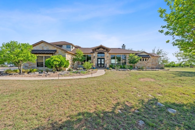 view of front of home featuring french doors, stone siding, a front yard, and a chimney