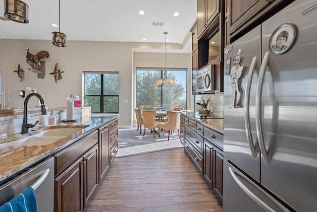 kitchen featuring visible vents, a sink, dark brown cabinetry, appliances with stainless steel finishes, and dark wood-style flooring