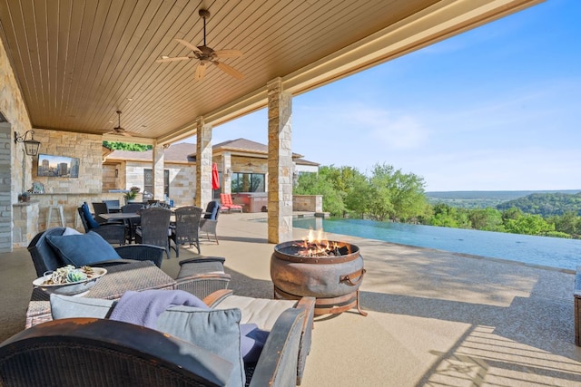 view of patio with ceiling fan, a fire pit, and outdoor dining space