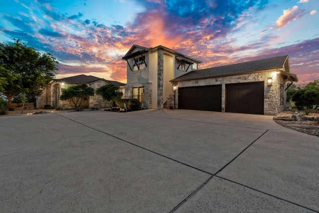 view of front of property featuring an attached garage, stone siding, and concrete driveway