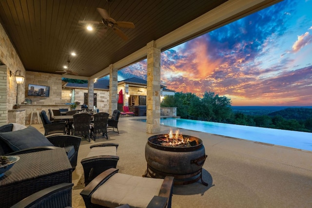 view of patio featuring a fire pit, an infinity pool, ceiling fan, and outdoor dining area