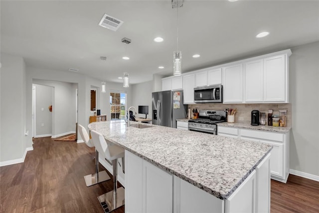 313 Brenham Pass, Georgetown, TX 78633 - kitchen with dark wood-style flooring, an island with sink, white cabinetry, baseboards, and appliances with stainless steel finishes